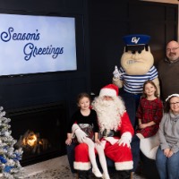 Family with 2 girls pose with Louie the Laker and Santa